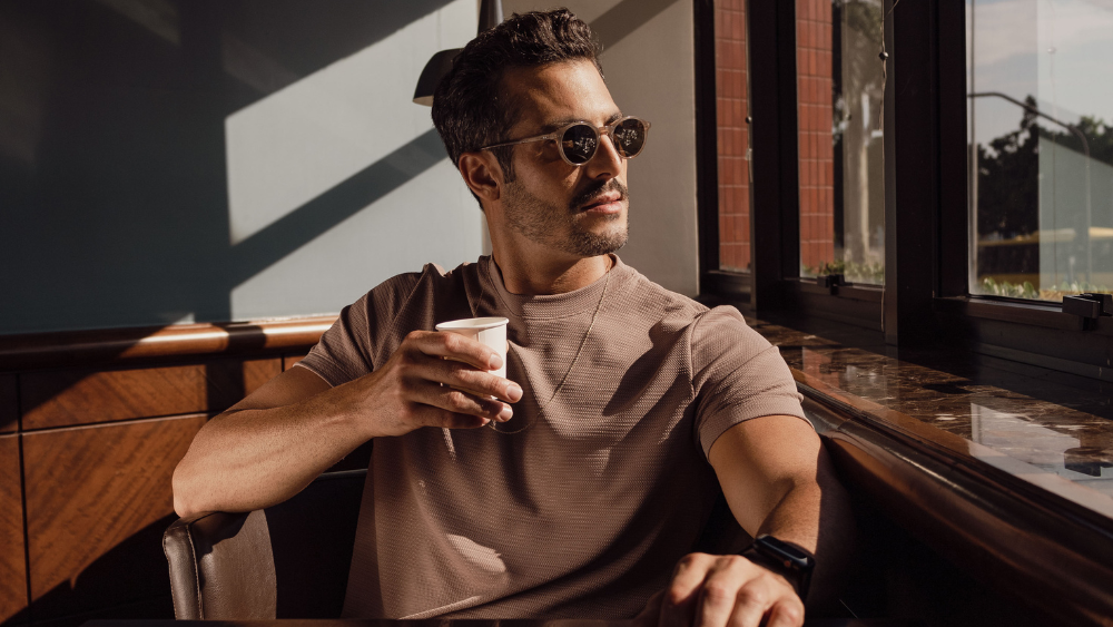 Homem usando camiseta de tecido tecnológico em ambiente urbano sofisticado, ilustrando elegância, conforto e inovação têxtil da Diklatex.