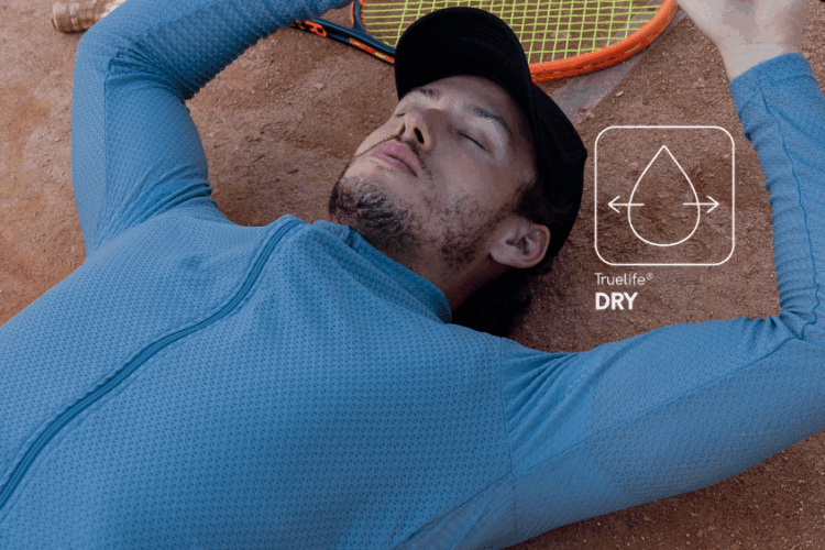 Homem descansando em quadra de tênis com camisa esportiva azul em tecido Diklatex com tecnologia Truelife® Dry, que garante secagem rápida e conforto durante atividades físicas.
