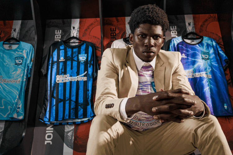 Modelo veste traje casual diante de camisetas esportivas produzidas com tecido sportwear, representando a fusão entre moda, performance e tecnologia têxtil.