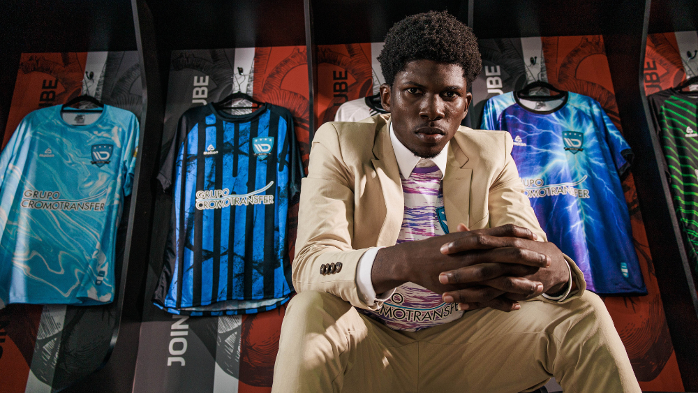 Modelo veste traje casual diante de camisetas esportivas produzidas com tecido sportwear, representando a fusão entre moda, performance e tecnologia têxtil.