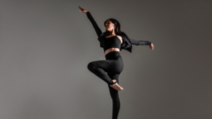 Mulher em movimento usando roupa esportiva preta de alta performance, ilustrando como a indústria têxtil pode reduzir o consumo de água com tecidos tecnológicos sustentáveis.