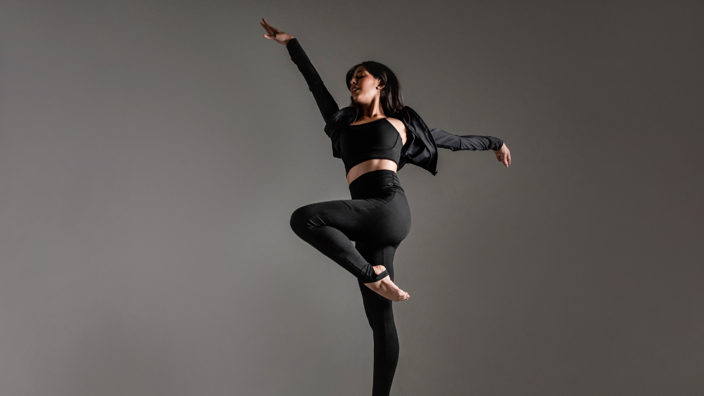 Mulher em movimento usando roupa esportiva preta de alta performance, ilustrando como a indústria têxtil pode reduzir o consumo de água com tecidos tecnológicos sustentáveis.