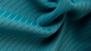 Tecido técnico azul-esverdeado com textura canelada e elasticidade, destacando estrutura e flexibilidade para roupas fitness de alta performance.