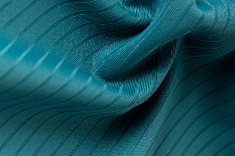 Tecido técnico azul-esverdeado com textura canelada e elasticidade, destacando estrutura e flexibilidade para roupas fitness de alta performance.