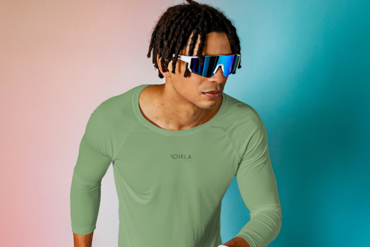 Homem usando camiseta esportiva verde de alta performance, desenvolvida com tecido técnico para activewear, com foco em conforto, elasticidade e controle de umidade.