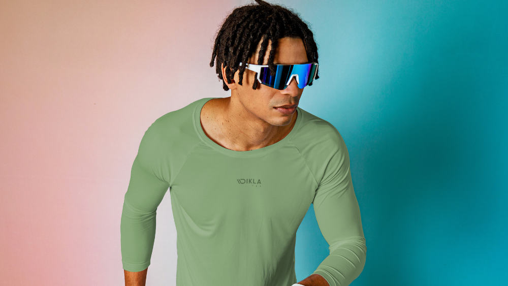 Homem usando camiseta esportiva verde de alta performance, desenvolvida com tecido técnico para activewear, com foco em conforto, elasticidade e controle de umidade.