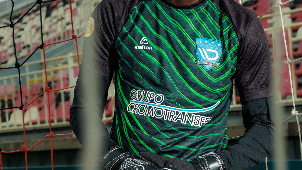 Atleta usando camisa esportiva preta com detalhes verdes em quadra, destacando tecido tecnológico desenvolvido para conforto, respirabilidade e performance esportiva.