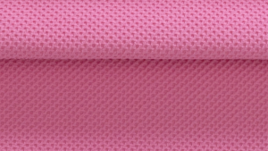 Close de um tecido esportivo rosa com textura tridimensional em padrão geométrico, destacando a estrutura da malha, o relevo da superfície e a dobra do material.