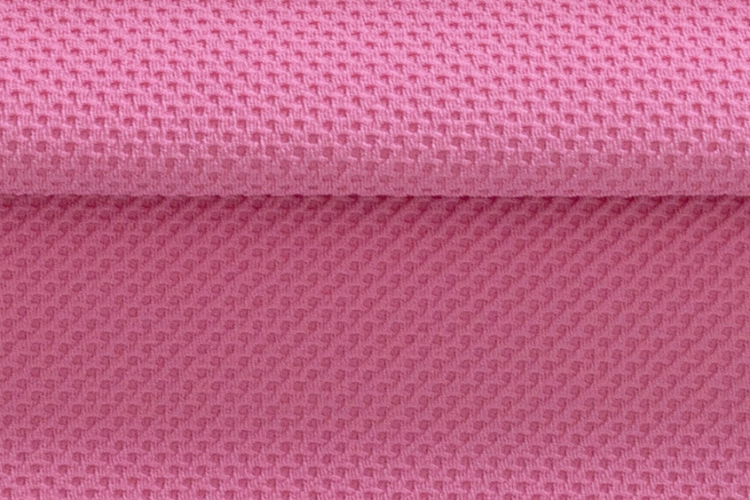 Close de um tecido esportivo rosa com textura tridimensional em padrão geométrico, destacando a estrutura da malha, o relevo da superfície e a dobra do material.