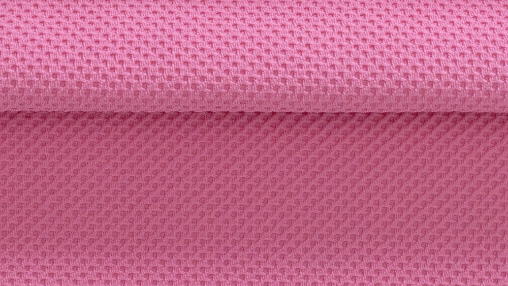 Close de um tecido esportivo rosa com textura tridimensional em padrão geométrico, destacando a estrutura da malha, o relevo da superfície e a dobra do material.