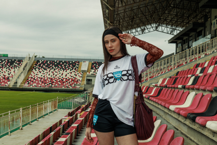 Mulher em estádio usando streetwear tecnológico que combina moda urbana, conforto e performance.