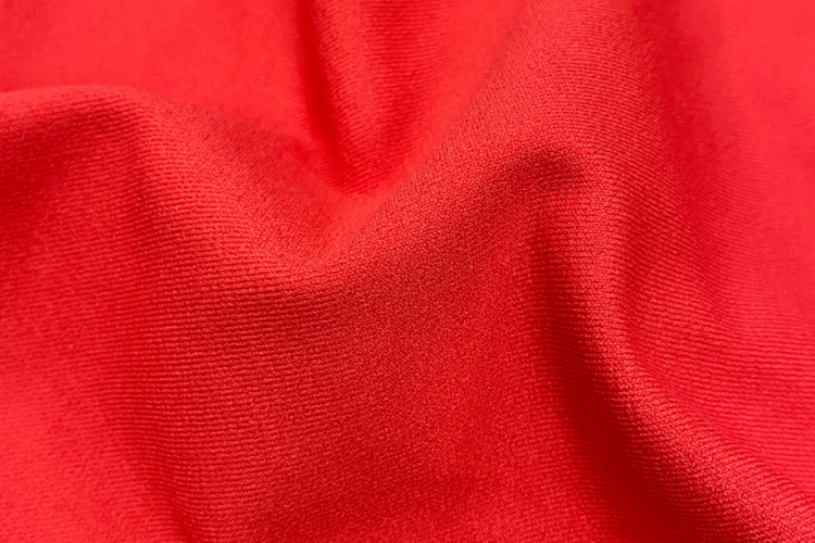 Tecido esportivo vermelho com textura e caimento para roupas de alta performance.