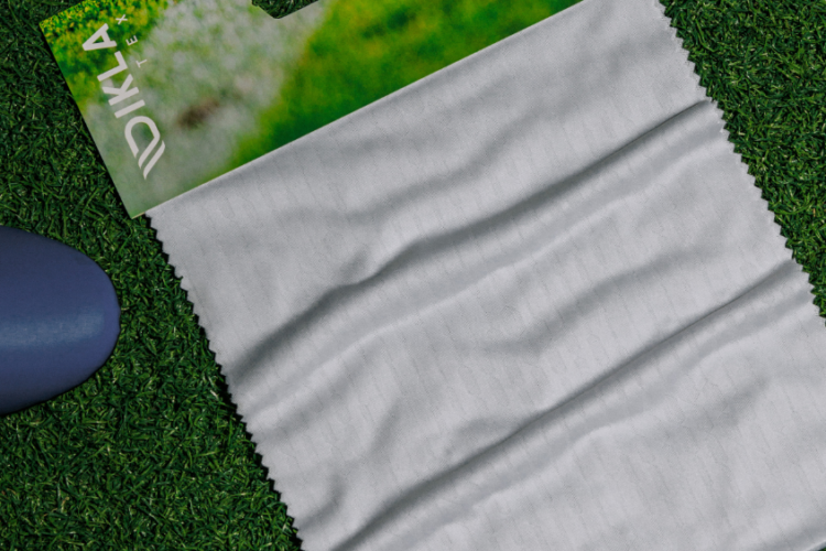Tecido para camisa de futebol profissional sobre gramado, com construção jacquard e textura esportiva.