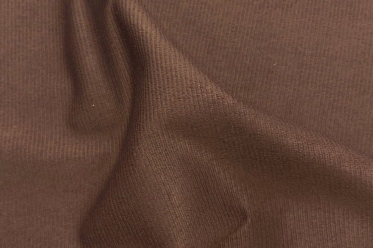 Tecido de alta compressão marrom em detalhe, destacando a textura da malha, sua estrutura e as ondulações do material.